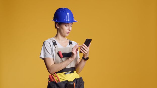 Portrait of woman engineer using smartphone to browse internet