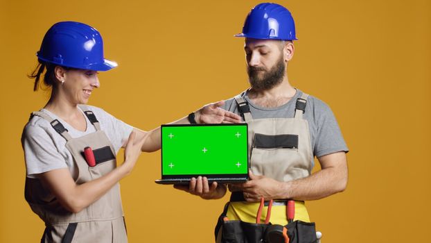 Team on builders holding laptop with greenscreen template