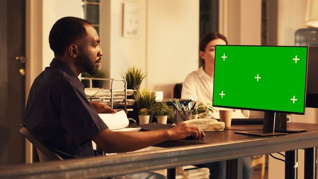 Male manager looking at computer with greenscreen display