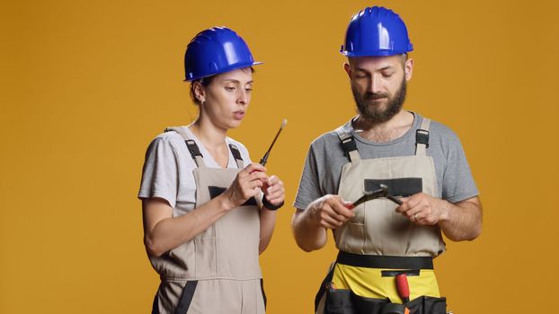 Man and woman builders using screwdriver and wrench