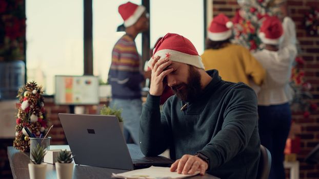 Stressed person trying to work in festive decorated office