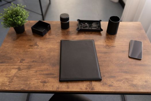 desktop in the office with a leather folder on a wooden surface