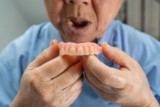 Asian senior or elderly old woman patient holding to use denture in nursing hospital ward, healthy strong medical concept