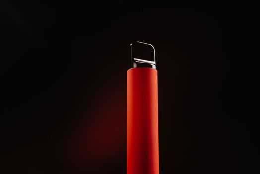 Red disposable e-cigarette on a dark background. Electronic vape, an alternative to smoking cigarettes. Colorful disposable electronic cigarette isolated on a white background. The concept of modern smoking, vaping and nicotine.