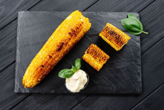 Grilled corn on a dark wooden background. Slices of sliced corn grilled on charcoal