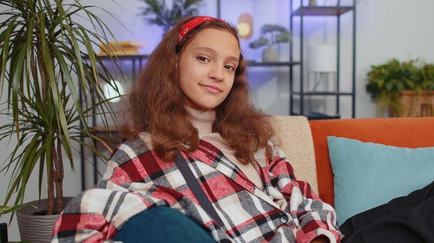 Close-up of happy beautiful preteen student girl child smiling looking at camera at home on couch