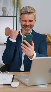Businessman shocked by sudden victory on smartphone, game winning, lottery goal achievemen good news