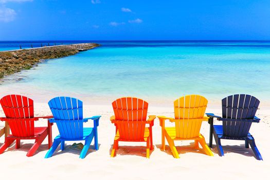 Colorful wooden chairs on white sand beach in Aruba, Duth Caribbean