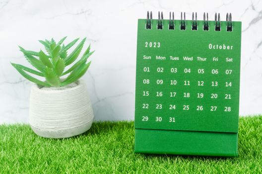 The Green October 2023 Monthly desk calendar for 2023 year on grass.