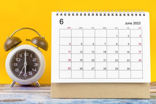 The June 2023 Monthly desk calendar for 2023 year and alarm clock.