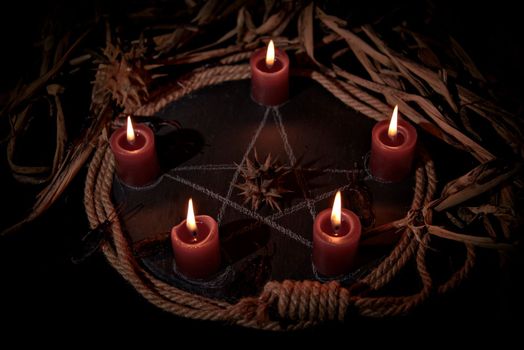 Voodoo doll, black candles, pentagram and old books on witch table. Occult, esoteric, divination and wicca concept. Mystic, voodoo and vintage background.