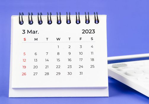 The March 2023 Monthly desk calendar for 2023 year with calculator on purple background.
