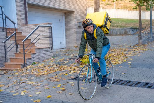 Delivery man riding bike delivering food and drink in town outdoors on stylish bicycle and yellow backpack.