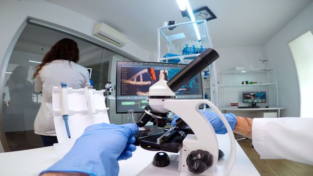 FPV of medical scientist looking under microscope, analyzes petri dish sample