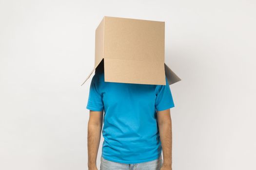 Unknown anonymous man wearing blue T- shirt standing with cardboard box on his head, having fun.