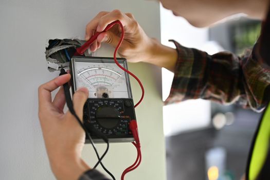 Electrician using a multimeter to test the electrical installation and power line current in an electrical system