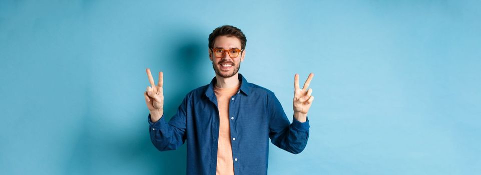 Cheerful guy posing with peace sign in new glasses, concept of eyewear shop promotion