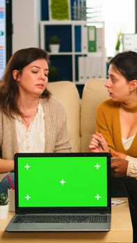 Businesswomen discussing in back of laptop with greenscreen