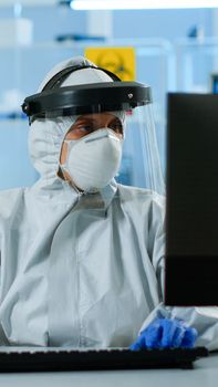 Laboratory technician assistant in ppe suit analyzing blood sample