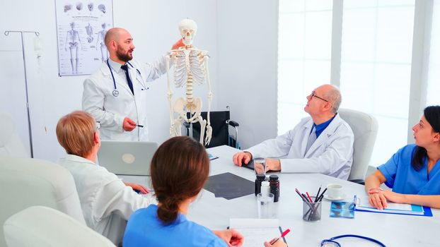 Expert radiologist demonstrating on skeleton during briefing