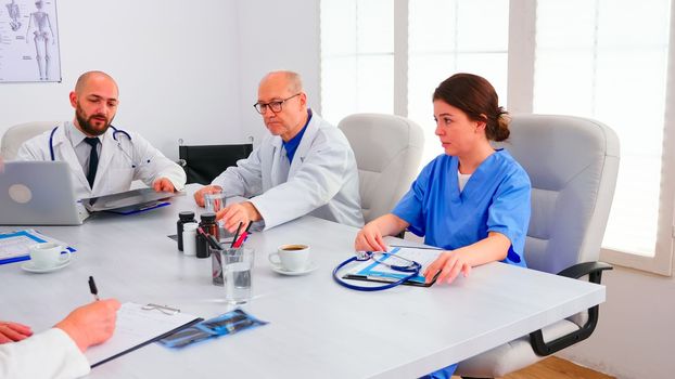 Expert doctor talking with medical staff in conference room