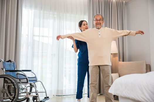 Old senior man enjoys training with physiotherapist for outstretched arms at home