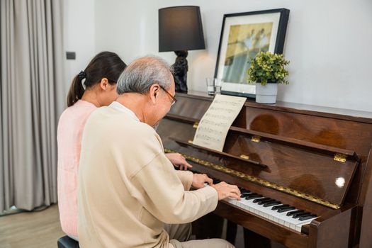 Asian young woman teaching piano for senior man teaching