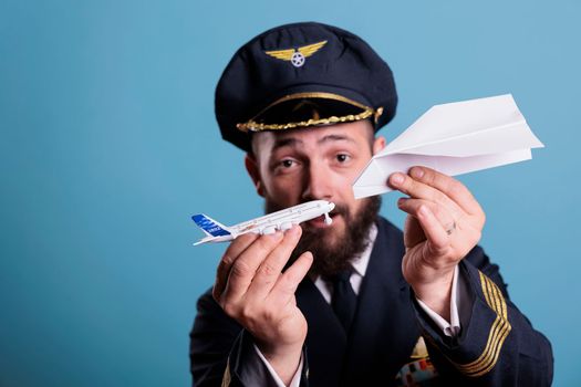 Airplane captain holding jet model and paper plane