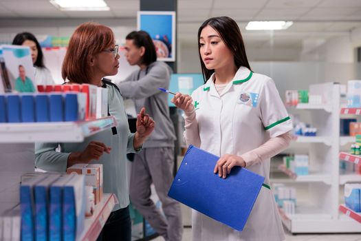 Asian pharmacist giving assistance to client in pharmacy