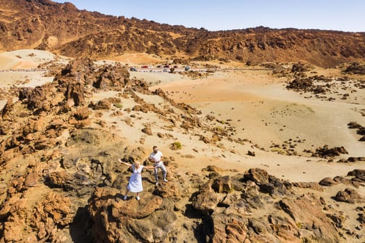 A married couple is standing in the crater of the Teide volcano. Desert landscape in Tenerife. Teide National Park. Tenerife, Spain
