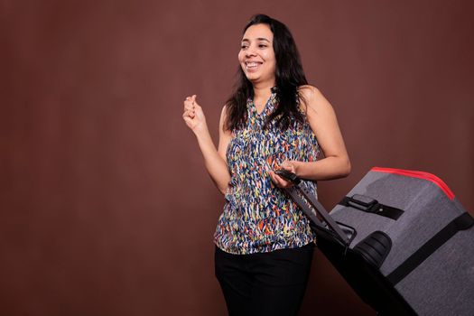 Happy indian traveler standing with wheeled suitcase