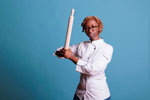 African american female baker holding rolling pin
