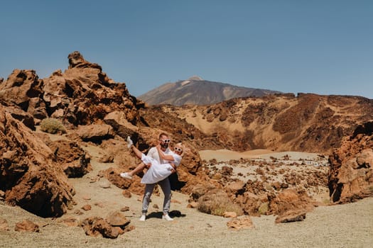 A married couple is standing in the crater of the Teide volcano. Desert landscape in Tenerife. Teide National Park. Tenerife, Spain