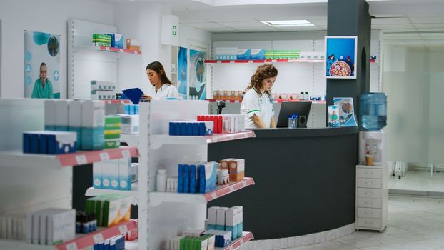 Diverse team of pharmacists working at drugstore counter to sell medicaments
