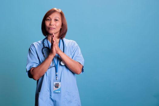 Religious medical assistant holding hands praying to god