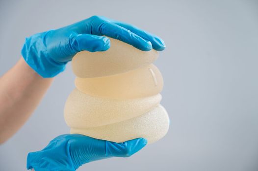 The plastic surgeon holds breast silicone implants.