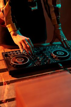 Woman disco jockey mixing sounds at dj turntables