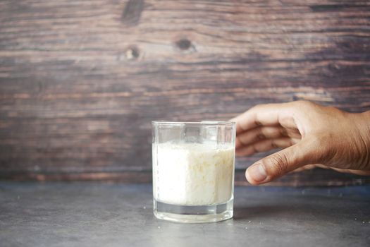 man hand holding glass of milk at early morning 