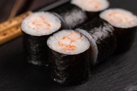 Maki shrimp sushi close-up. Shrimp fillet stuffing wrapped in rice and nori seaweed. Japanese cuisine