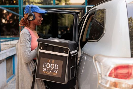 African american smiling courier delivering takeaway food by car
