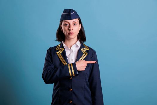 Professional stewardess pointing at side with index finger