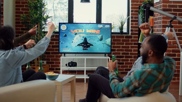 Cheerful friends celebrating online gaming win on console