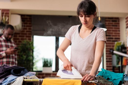 Serious woman concentrating on ironing clothes at home