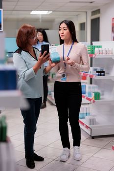 Pharmacist working in drugstore with elderly client