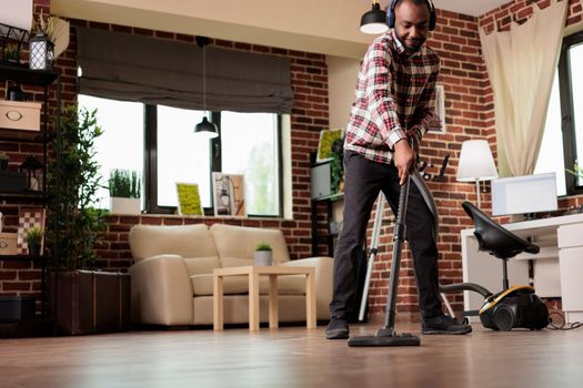 African american man vacuuming dust at home