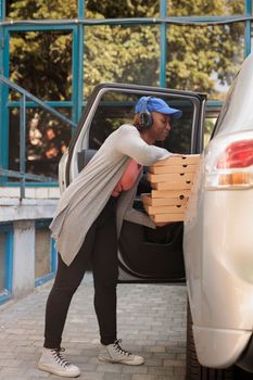 African american restaurant courier delivering pizza by car