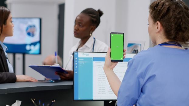 Medical assistant holding smartphone with greenscreen display