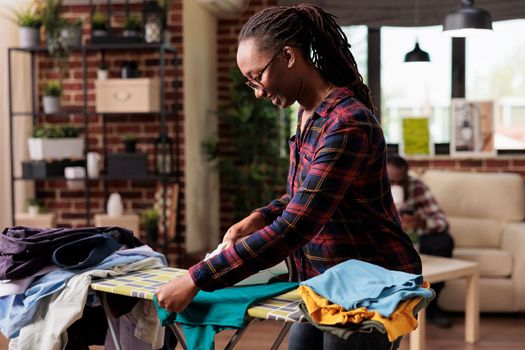 Optimistic african american woman does household chores