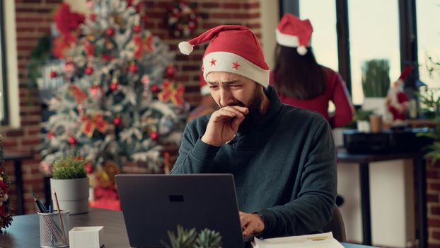 Male worker analyzing information on laptop in festive workplace