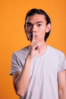 Young asian man showing silence gesture